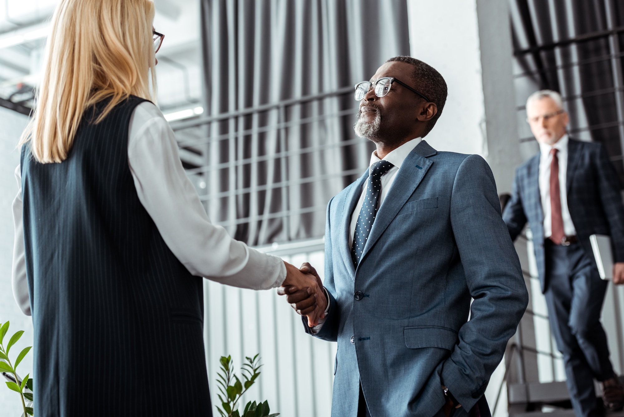 low angle view of blonde businesswoman shaking hands with african american businessman
